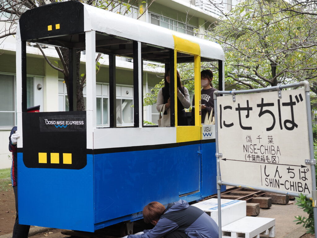 手作りの電車の模型に乗る来場者